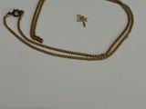 gros plan d'un collier en or avec une chaîne sur une surface blanche