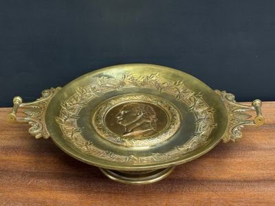 brass plate with a picture of a man on it on a wooden table