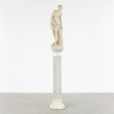une statue représentant un homme debout au sommet d'un socle blanc