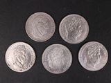 four silver coins sitting on top of each other on a black surface