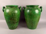 pair of green vases with handles sitting on a white surface