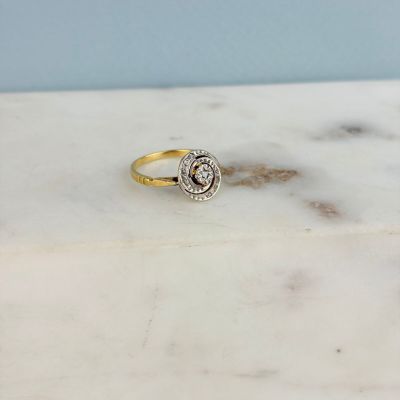 un gros plan d'une bague en or et diamants posée sur une surface en marbre