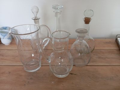 bottles and glasses on a wooden table with a cell phone in the background