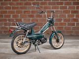 an image of a small motor bike parked in front of a brick wall