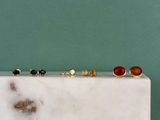 cinq paires de boucles d'oreilles posées sur un bloc de marbre