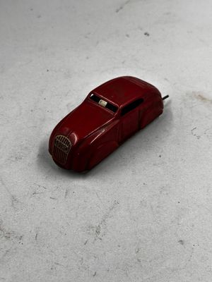 une petite voiture rouge posée sur une surface blanche