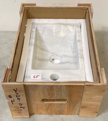une caisse posée par terre, avec un lavabo à l'intérieur
