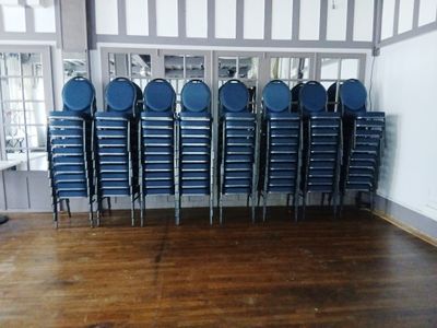 des rangées de chaises en plastique bleu dans une pièce au sol en bois
