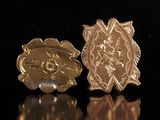 un gros plan sur une paire de broches en or posées sur une surface noire