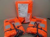 trois gilets de sauvetage orange posés les uns à côté des autres sur une table
