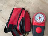 un sac rouge et noir et un compteur rouge et noir posés sur une table en bois