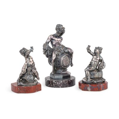 trois figurines en argent représentant une femme et un enfant, posées sur des socles en marbre