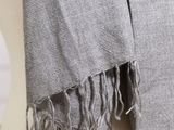 a gray blanket with fringes on it on top of a chair