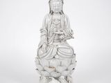 une statue blanche représentant une femme assise sur une fleur de lotus