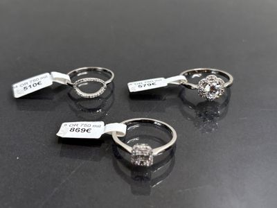 trois bagues en diamant posées sur un fond noir, accompagnées d'une étiquette de prix