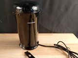 a coffee grinder and a measuring spoon sitting on a table