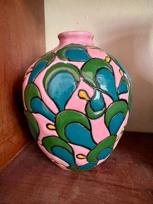un vase rose et vert posé sur une étagère contre un mur