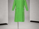 une photo d'un manteau vert posé sur un présentoir à mannequin dans une pièce