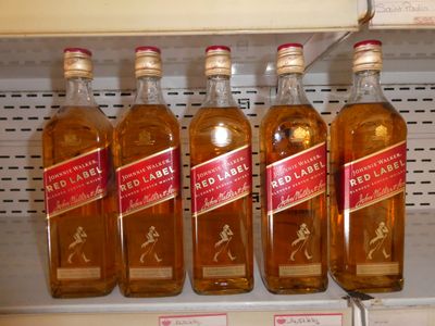 quatre bouteilles de whisky « Red Label » sur une étagère dans un magasin