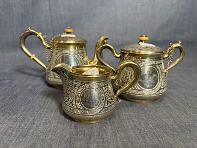 trois théières anciennes en métal argenté sur fond gris
