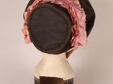 a black hat with a pink ribbon on top of it