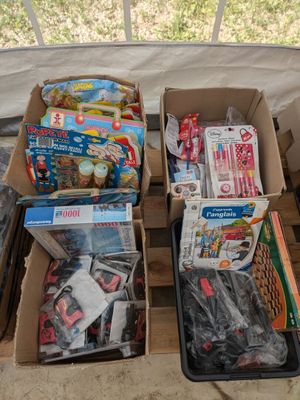 Plusieurs cartons de jouets sont posés sur une palette devant une fenêtre.