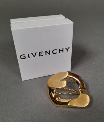 a close up of a gold brooch with a box in the background