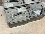 plusieurs batteries posées sur un sol carrelé, à côté d'une borne d'incendie