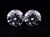 a pair of round cut diamonds on a black surface