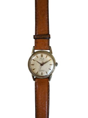 une vieille montre avec un bracelet en cuir marron sur fond blanc