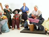 many figurines of people that are sitting on a bench