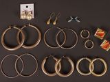 several pairs of gold hoop earrings and earrings on a black surface