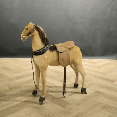 Petit cheval d'enfant gainé de peau, monté sur roulettes.