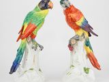 une paire de figurines colorées représentant des perroquets, perchées sur une souche d'arbre