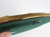 a person holding a green purse with a gold handle