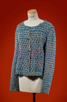 a blue sweater on a mannequin stand against a red background