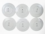 four white plates with a black dot on each of them
