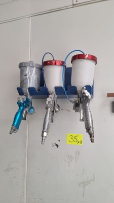three spray guns hanging on the wall next to each other