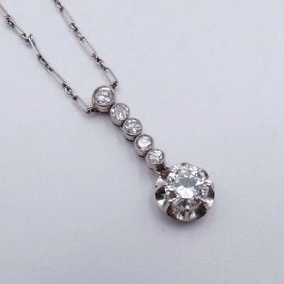 un gros plan d'un pendentif en diamant suspendu à une chaîne, posé sur une surface blanche