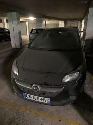 une voiture noire garée dans un parking à étages, à côté d'autres voitures