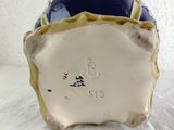 a blue vase with a white base and a gold rim