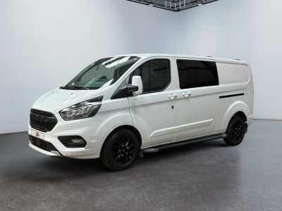 Une camionnette blanche est garée dans une pièce blanche au sol noir.