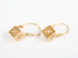 une paire de boucles d'oreilles en or serties de diamants, posées sur un fond blanc