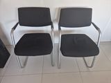 pair of black office chairs with chrome legs and arms