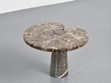 a marble table with a circular top on a gray floor