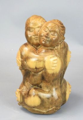 two figurines of two people hugging each other on a white surface