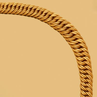 une image montrant un gros plan d'un collier en or sur fond beige