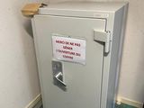 a safe box with a sign on it in the corner of a room