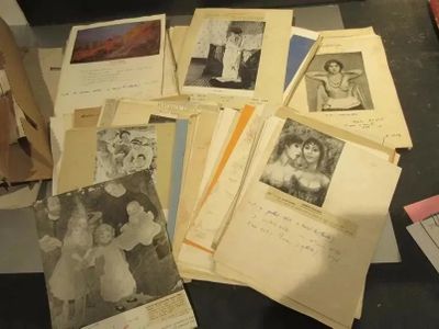 une pile de vieilles photos posée sur une table, à côté d'une pile de papiers