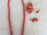 necklace, earrings, and bracelet with coral beads on a white surface